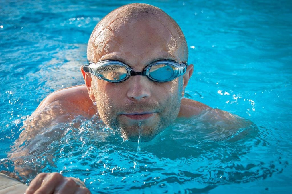 Man doet aquagym oefening in zwembad met aquagym materiaal voor fitnesstraining